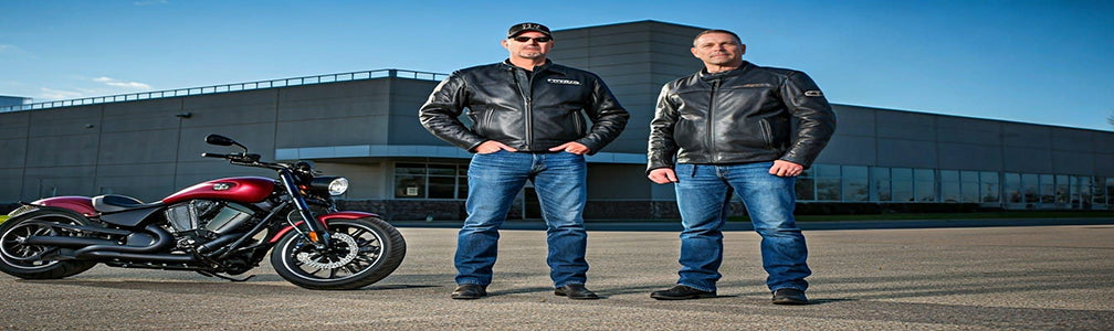 2 men standing next to a Victory motorcycle in front Of the Victory motorcycle plant at Spirit Lake Iowa.