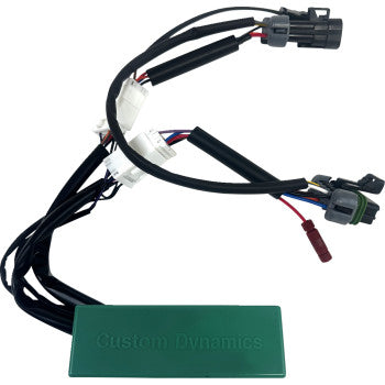 The Polaris RZR Pro Module Run Turn Brake by Custom Dynamics is a green rectangular electronic module with plug-and-play connectors and black cables for easy integration into vehicle wiring to control rear brake lights and custom flash patterns.
