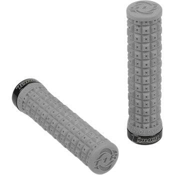 The Defy Lock On Grips Soft Gray Black by Torc1 are gray, cylindrical bike handlebar grips with a tacky compound and raised square pattern featuring small star-shaped bumps. Both grips have black end caps for secure fit; one lies flat, the other stands upright.