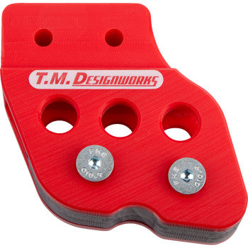 The Honda-Yamaha-Kawasaki-Suzuki Chain Guide Red by T.M. Designworks features a durable red plastic bracket with three large holes, two top mounting holes, metal screws, white logo on the front, and UV protection for long-lasting use.