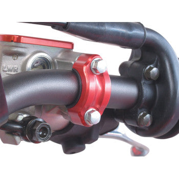 Close-up of the Bar Clamp Rotating Red by Works Connection, crafted from 6061 T-6 aluminum with a red metallic finish, secured by two bolts to the handlebar near the throttle, front brake, and control cables.