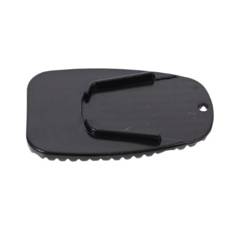 The Motorcycle Kickstand Pad by Witchdoctors is a small, flat black plastic pad with a jagged edge, two raised prongs, and a corner hole—perfect as a universal base for added kickstand stability.