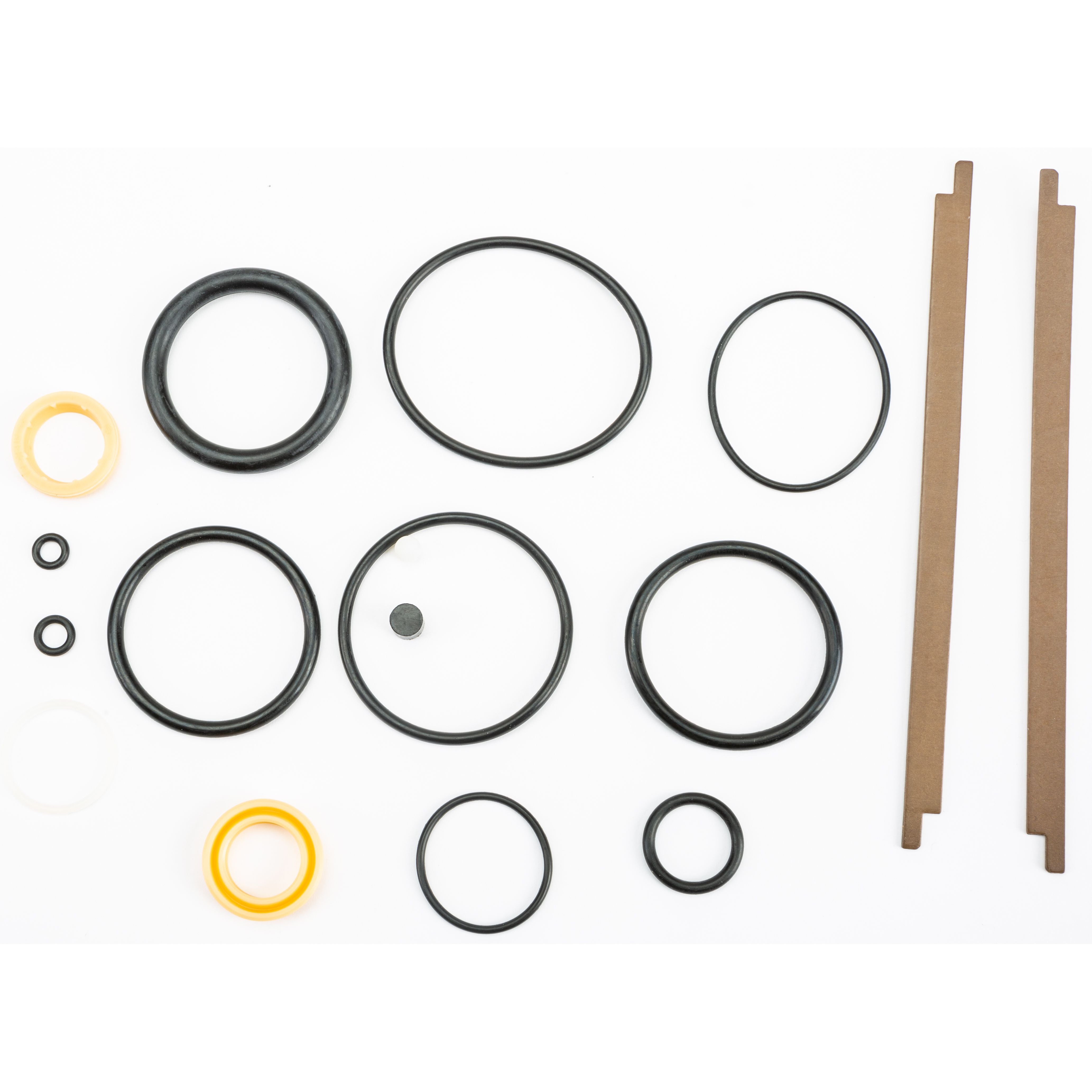 The UTV OE Shock Rebuild Kit Replacement Parts by Fox includes assorted rubber O-rings, washers, and two thin brown rectangular strips in various sizes and colors—mainly black, with some yellow and white—all neatly arranged on a white background.