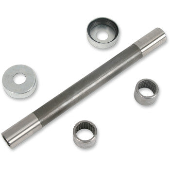 A Pivot Works Swingarm Bearing Kit is displayed on a white background, showing a steel shaft with two needle bearings, two metal washers, and two circular metal seals arranged to OEM specs for suspension control linkage.