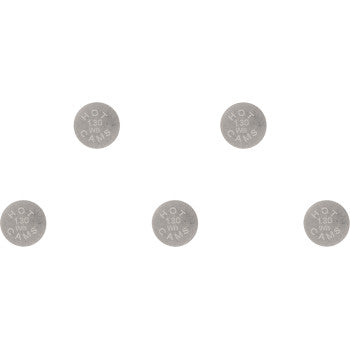 Five small round metallic valve shims with engraved size markings arranged on white background.