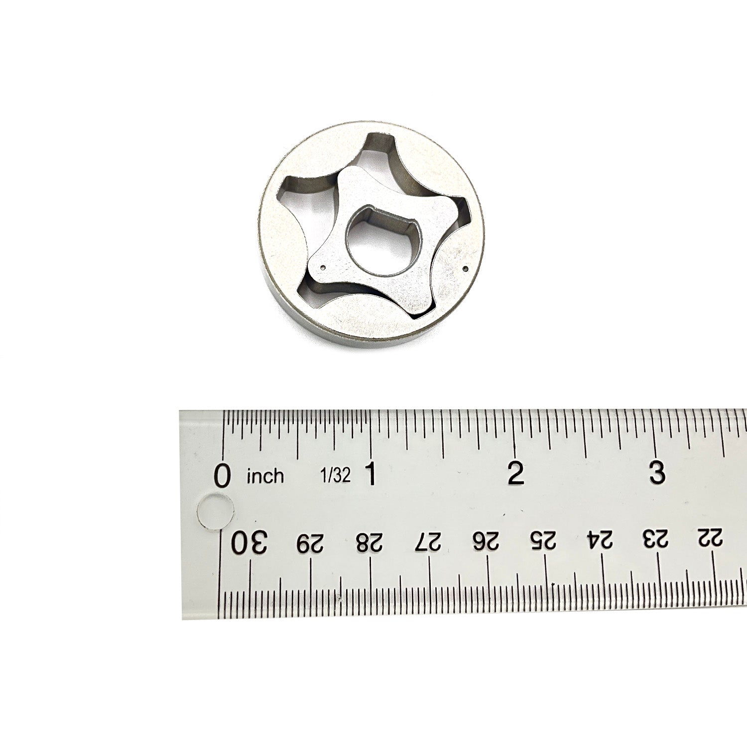 Silver metal gerotor gear with star-shaped inner rotor, shown next to a ruler for scale.