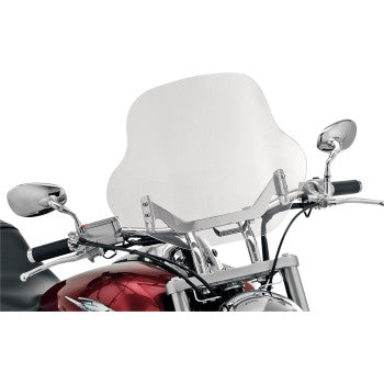 A close-up shows a motorcycle’s handlebars with chrome side mirrors, part of its red fuel tank, and a large Batwing Windshield - 15 - Clear by Slipstreamer mounted with universal hardware.