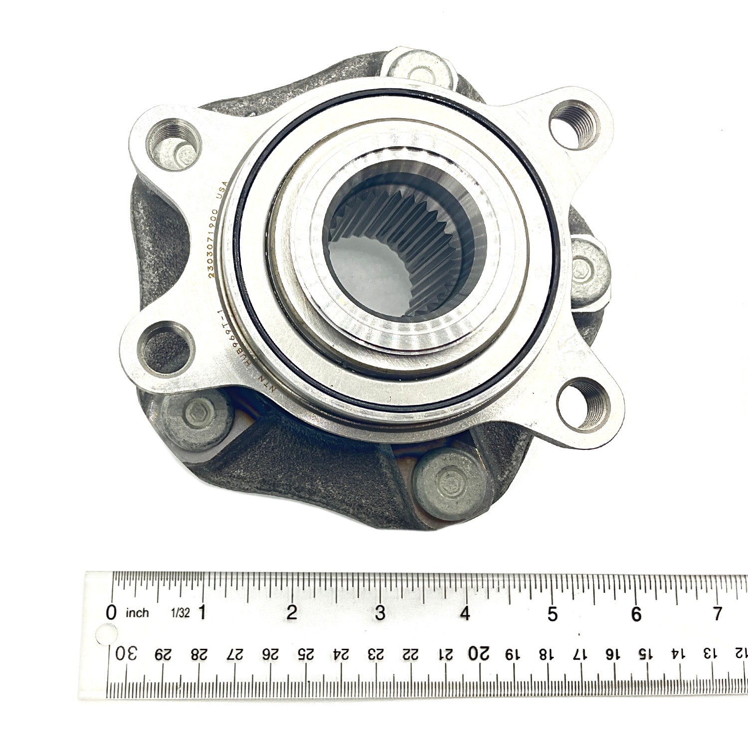 Silver metal unitized hub with circular bearing and five evenly spaced bolt holes, placed above a ruler for scale.