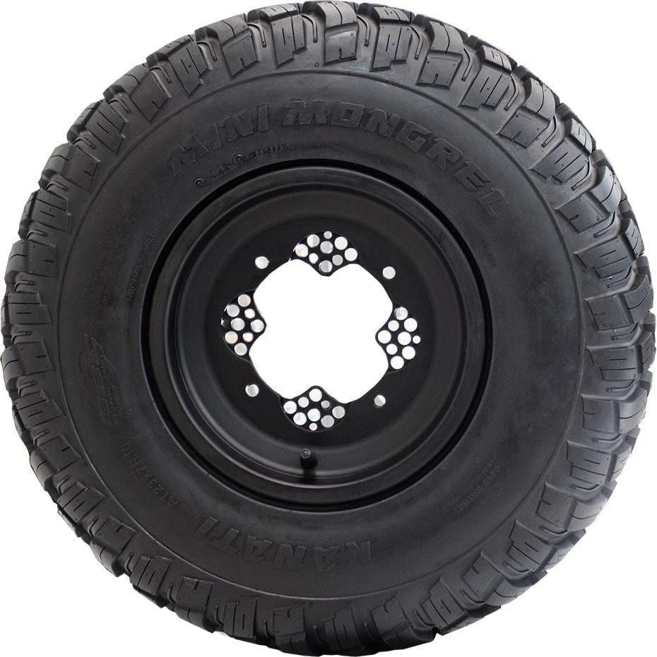 The GBC Tire Mini Mongrel 23X7-10 is a large off-road tire with deep treads for superior traction, mounted on a black metal wheel with multiple bolt holes. Mini Mongrel and Kanati are printed on the sidewall.