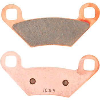 Set of two copper-colored metal brake pads with friction material surface, each featuring mounting holes and stamped code.