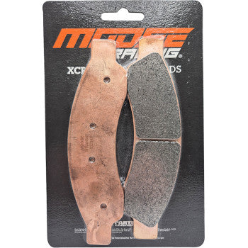 Copper-colored metal backing plates with black friction material brake pads on black Moose Racing branded backing card.