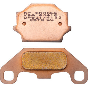 Two copper-colored Kawasaki - Suzuki RDP Racing Brake Pads by DP Brakes: one shows the stamped metal backing, while the other displays the sintered metal friction surface.