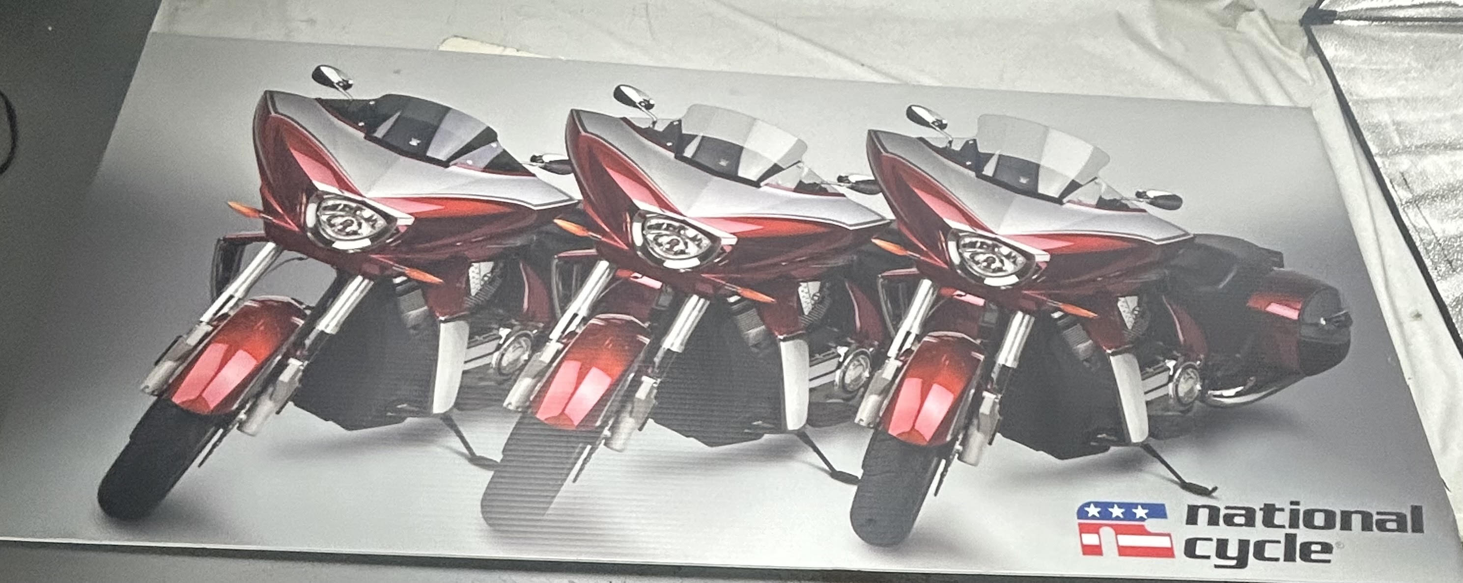Gray National Cycle banner featuring three red, black, and white motorcycles and a brand logo on the right.