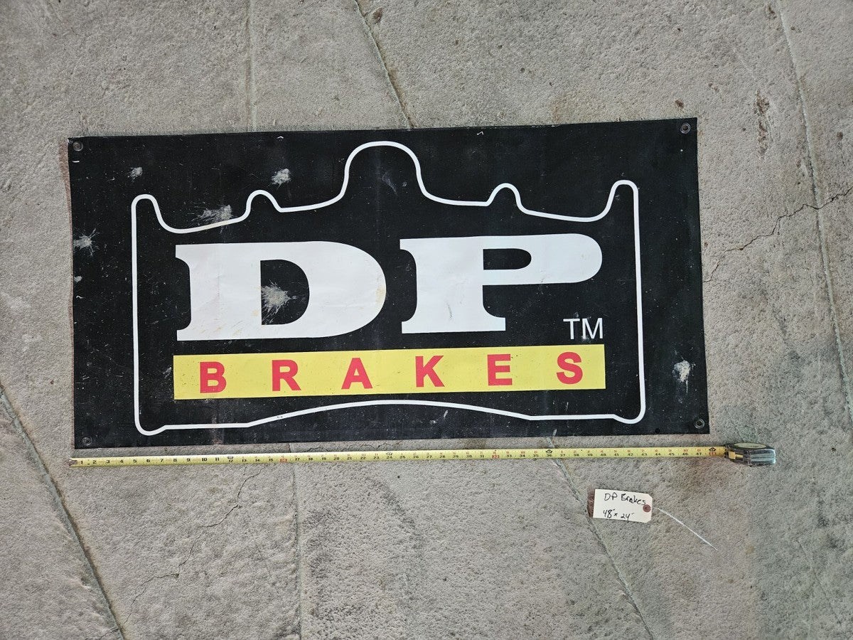 Black rectangular DP Brakes banner with a large white logo, red-and-yellow lettering, and a thin yellow lower border.