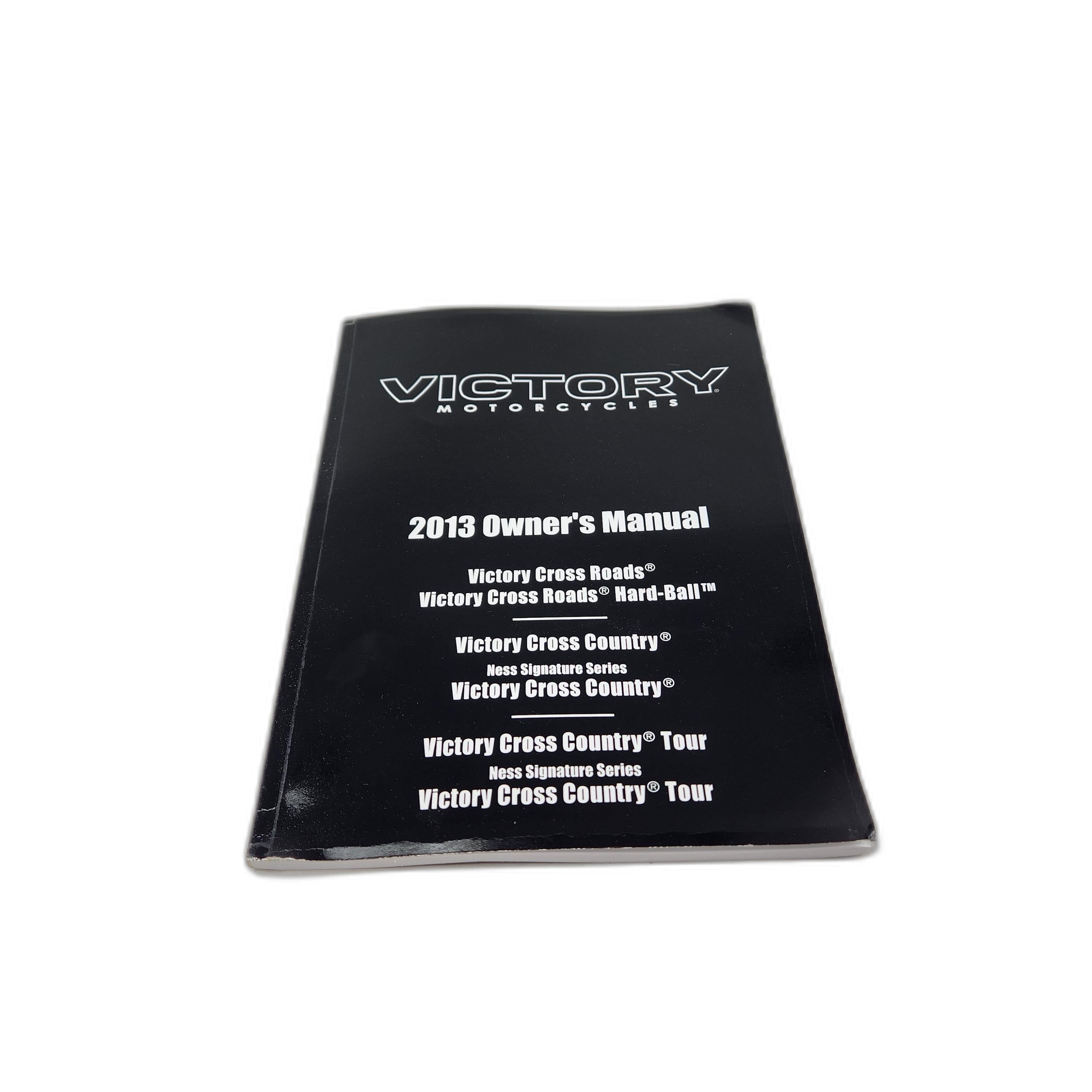 A black 2013 Owners Manual for Polaris Victory Cross Country/Cross Roads, perfect for finding OEM parts. Shown on a white surface.