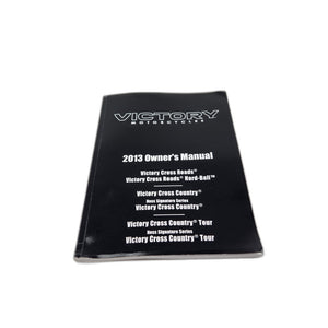 A black 2013 Owners Manual for Polaris Victory Cross Country/Cross Roads, perfect for finding OEM parts. Shown on a white surface.
