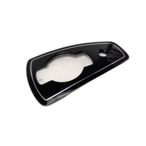 The Badge-Console Rr GlBlack by Polaris is a glossy black rectangular plastic trim piece with a center cutout and small circular hole, shown on a white background. Ideal as an OEM part for your Indian motorcycle.