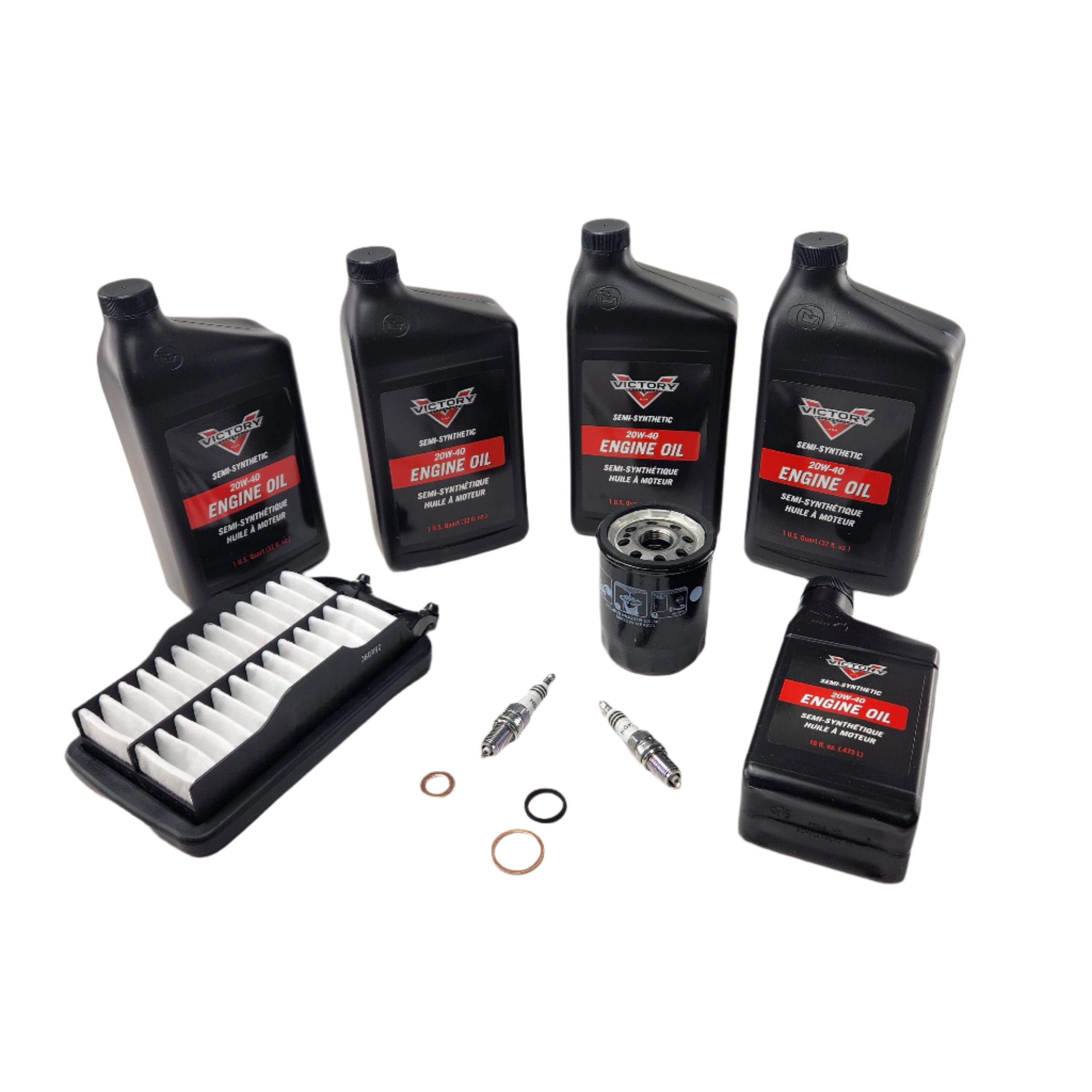 Five black engine oil bottles, an air filter, oil filter, two spark plugs, and three copper washers on a white background—everything in the Witchdoctors Motorcycle Maintenance Kit for Victory Cross Bikes 2008-UP.