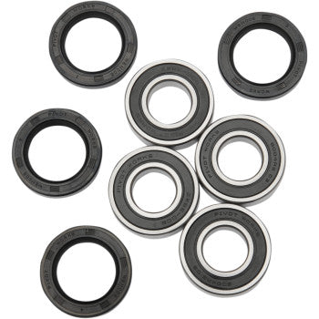 Set of round metal wheel bearings and black rubber seals arranged on white background.