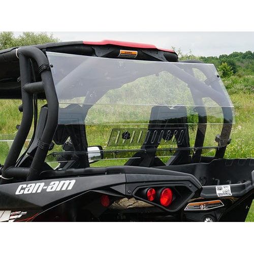 A black Can-Am with a Spike Vented Rear Windshield is parked on green grass among trees under a cloudy sky, providing enhanced protection and visibility.