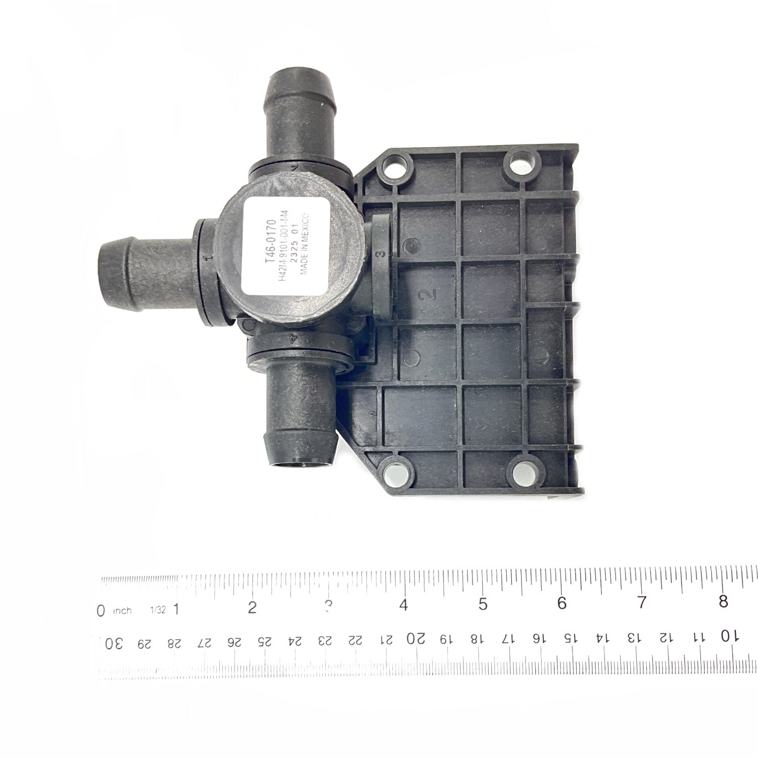 Black plastic 3-way valve with grid-pattern mounting plate and three hose connectors next to ruler.
