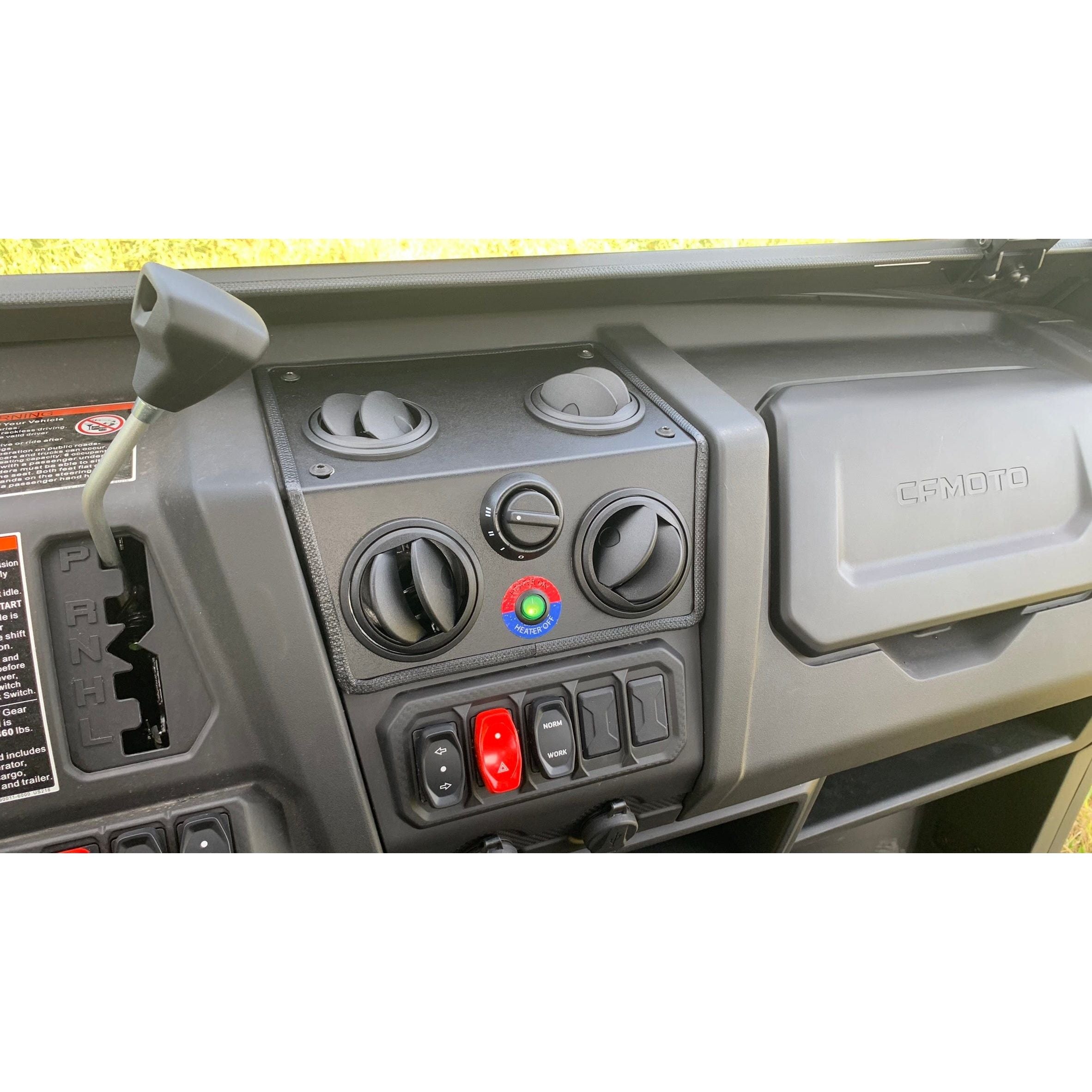 The image shows a CF Moto UTV cab dashboard with air vents, a gear shifter, switches and knobs for the Heater by Open Trails climate control, a CFMOTO-labeled glove compartment on the right, and visible polycarbonate door panels.