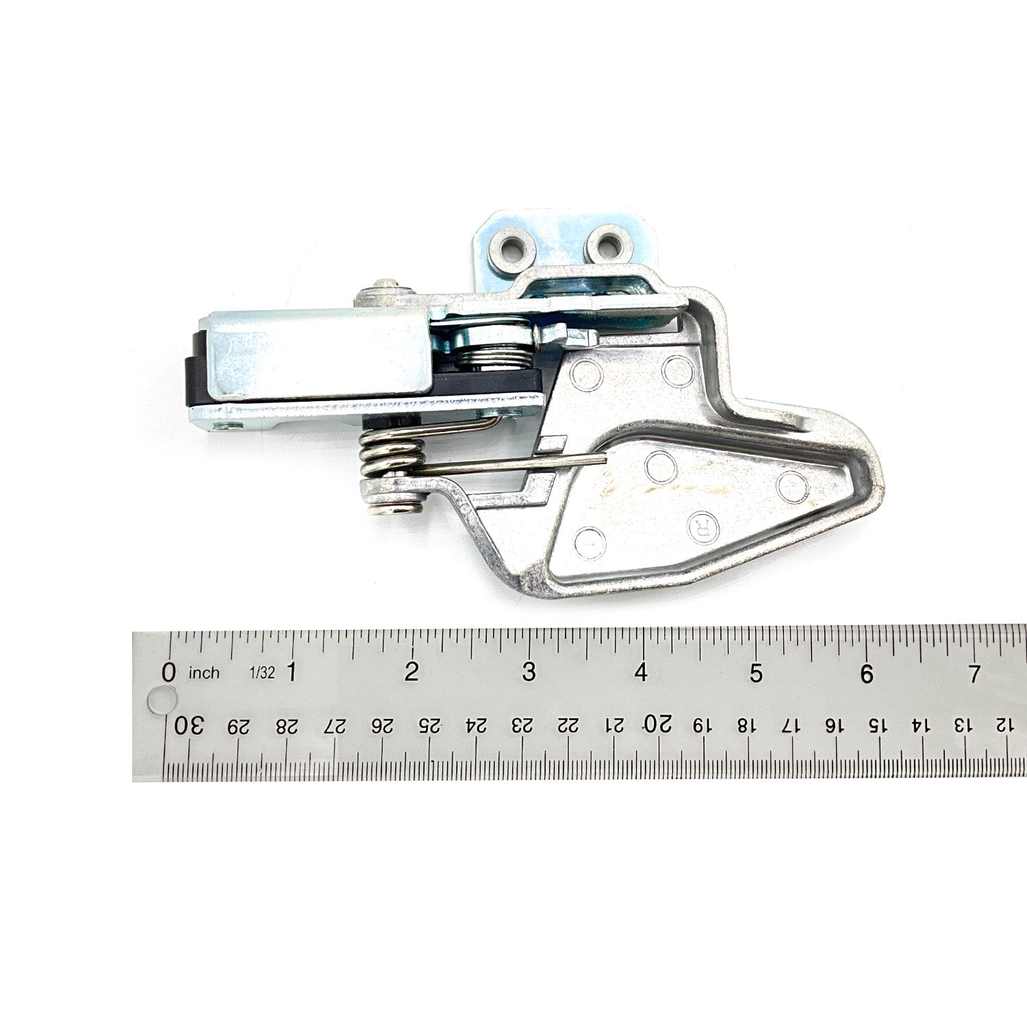 Silver metal door latch with spring mechanism and mounting holes shown next to a ruler for size reference.