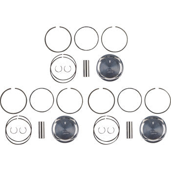Set of three silver metal pistons with black tops, each accompanied by matching piston rings and two small cylindrical pins.