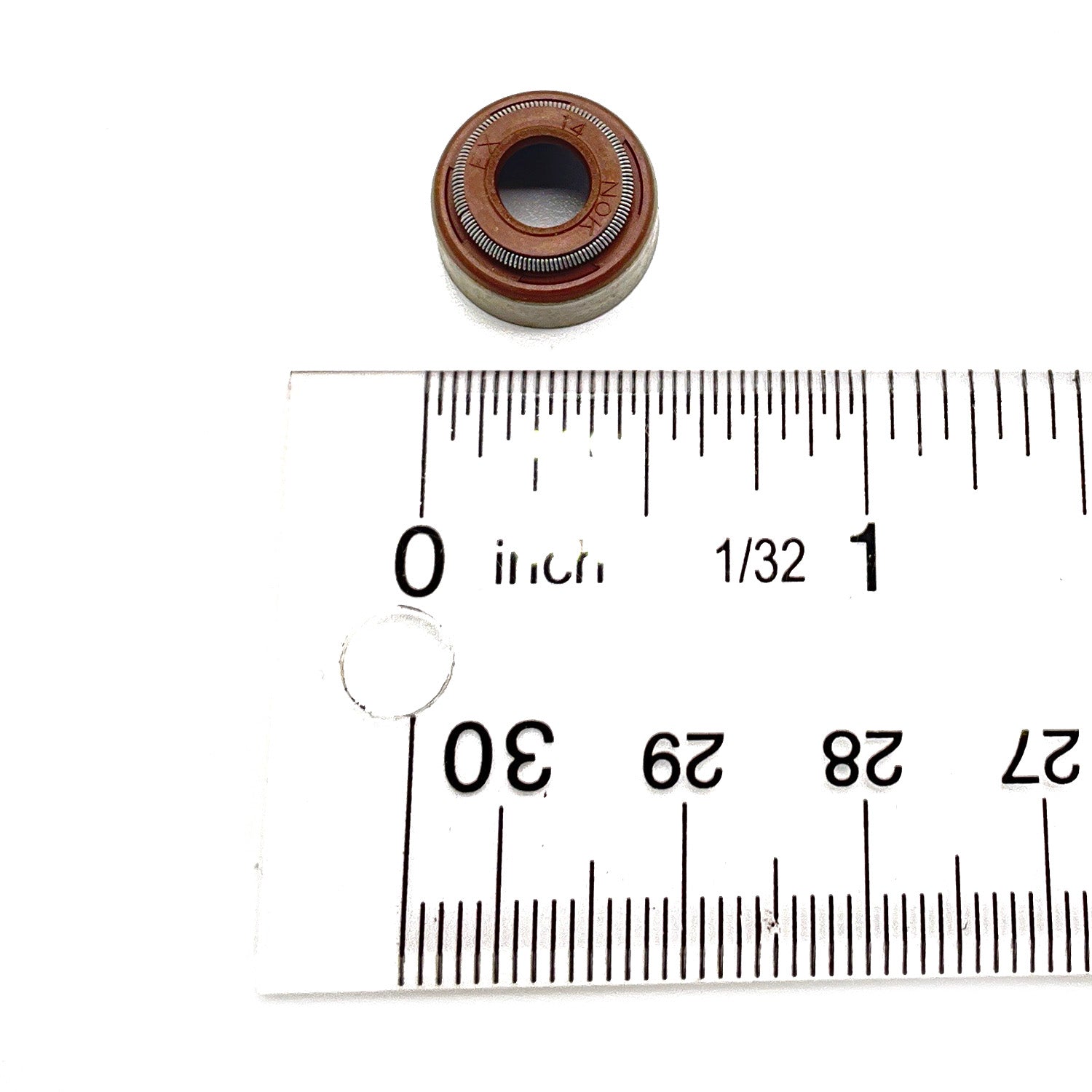 Brown rubber and metal exhaust valve seal next to white ruler showing size under 1 inch.