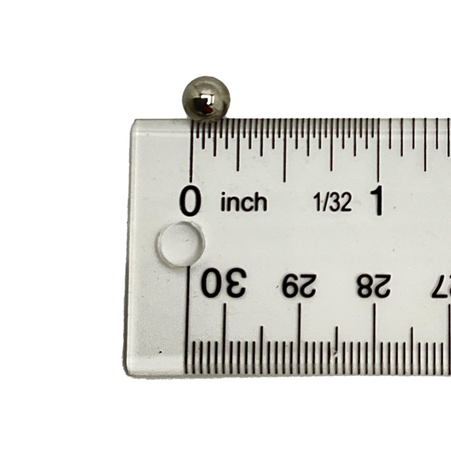 Small shiny steel ball bearing positioned at zero inch mark on clear ruler with black markings.