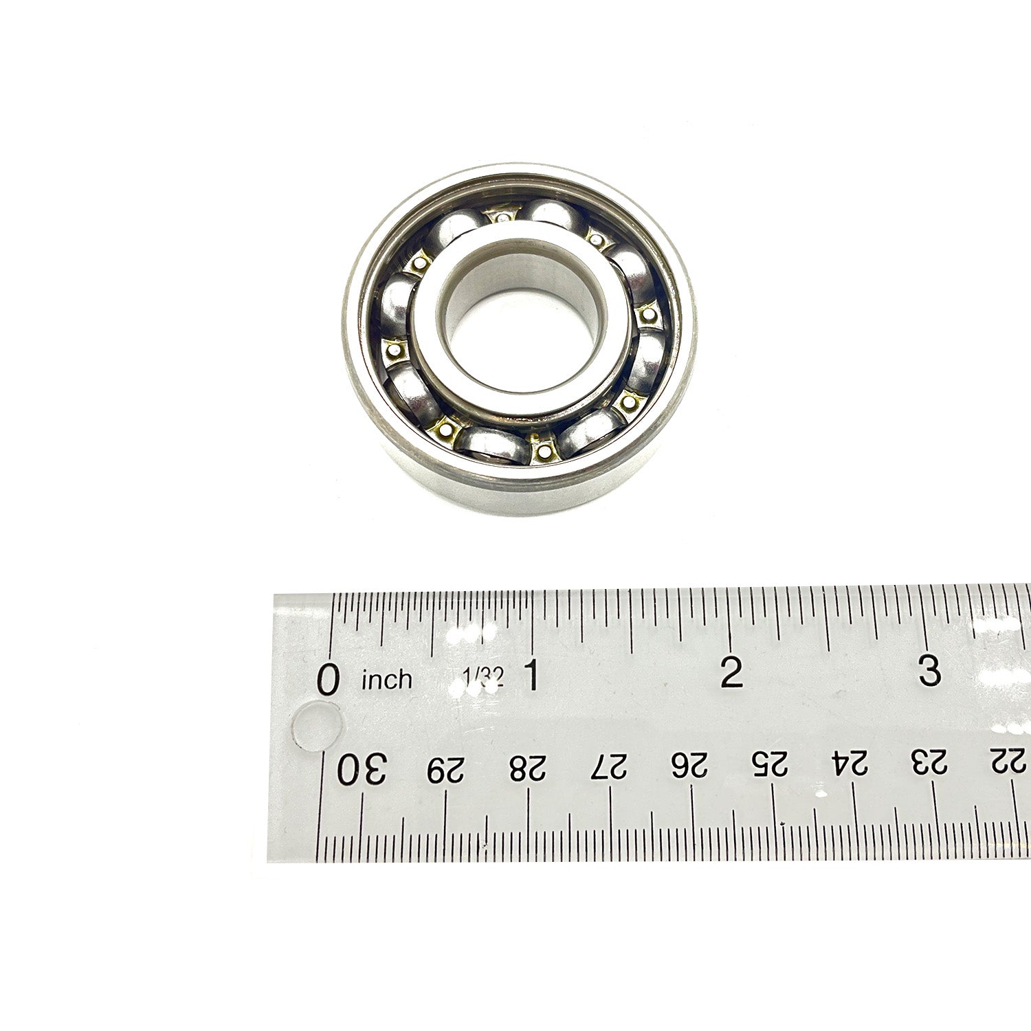 Metal ball bearing with visible steel balls inside circular race, next to silver ruler for size.