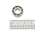 Metal ball bearing with visible steel balls inside circular race, next to silver ruler for size.
