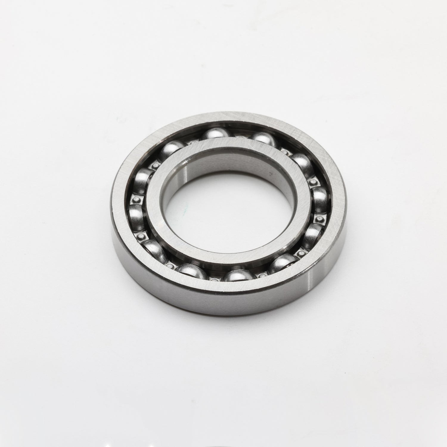 Silver metal ball bearing with visible steel balls and circular outer race.
