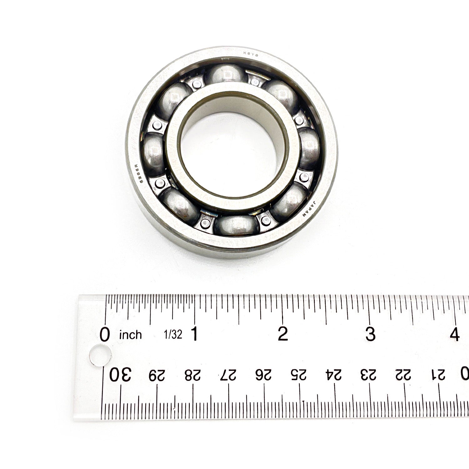 Steel ball bearing with visible metal balls inside circular frame next to white ruler showing size.