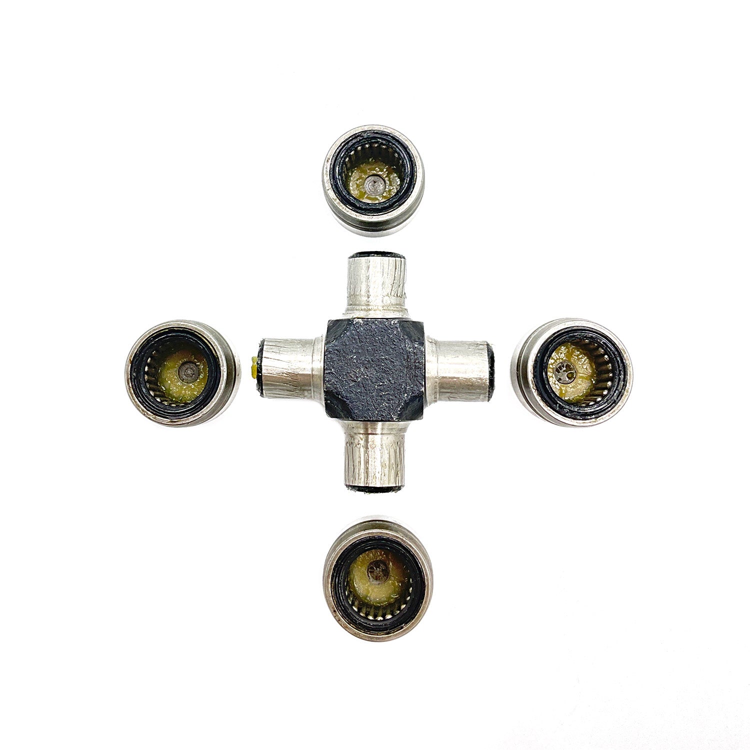 Metal universal joint with four cylindrical caps, cross-shaped body, and visible needle bearings inside caps.