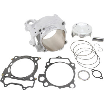 Silver cylindrical engine block with polished interior, piston, piston rings, gaskets, and small metal clips laid out on a.