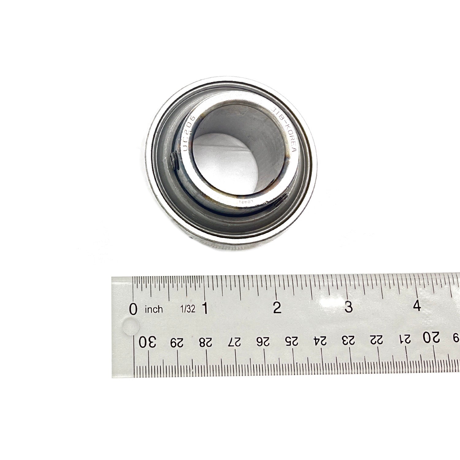 Silver metallic cylindrical front prop bearing with a hollow center next to a metal ruler showing its size.
