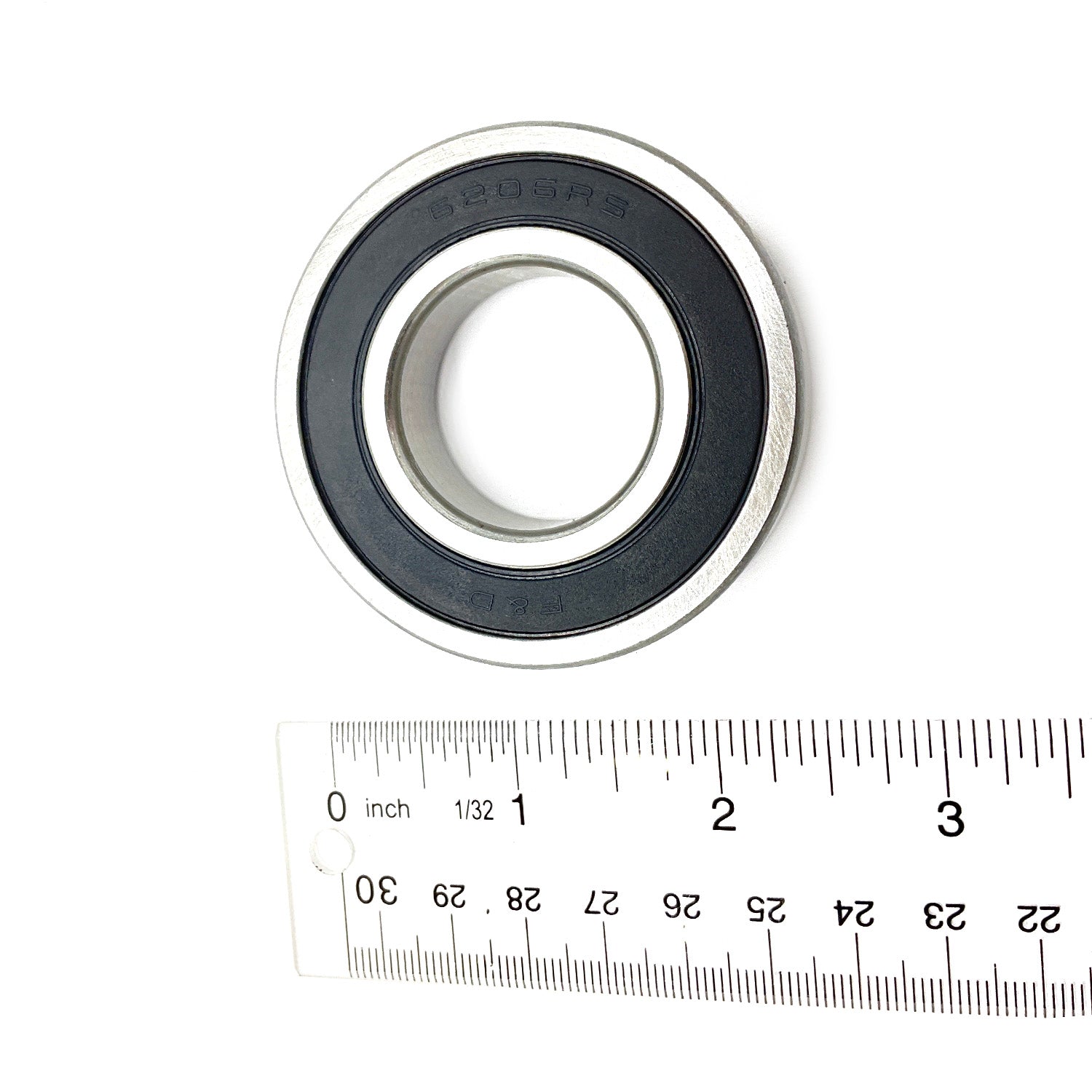 Sealed steel ball bearing with black rubber seal and silver outer ring next to a ruler for scale.