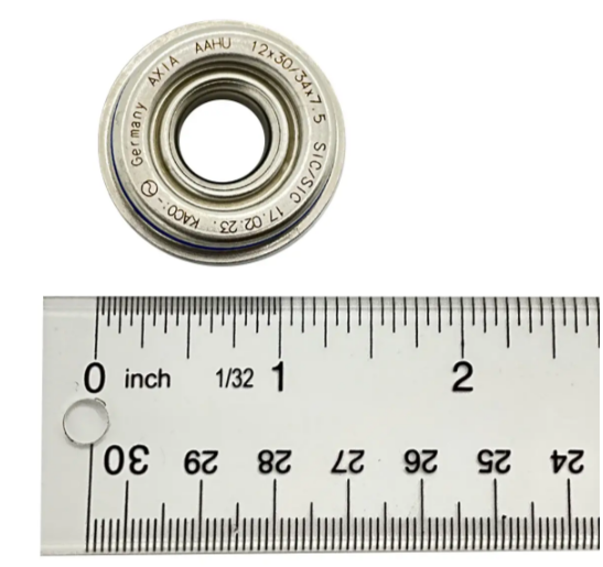 A Polaris Seal, Wp Shaft is shown above a ruler marked in inches and centimeters for scale. The seal features engraved text on its edge and its diameter appears to be slightly over 1 inch.
