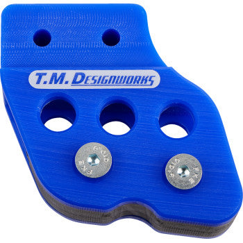 The T.M. Designworks Blue Chain Guide for Honda, Yamaha, Kawasaki, and Suzuki features three large holes, two screws, UV protection, and white-blue T.M. Designworks branding across the top.