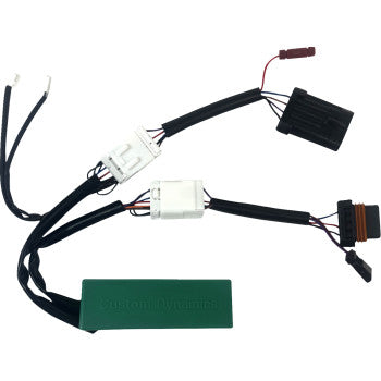 The Polaris General Triple Play Module by Custom Dynamics is a black wiring harness with plug-and-play connectors and a green rectangular module, featuring multiple wires for rear brake lights and plastic plugs.