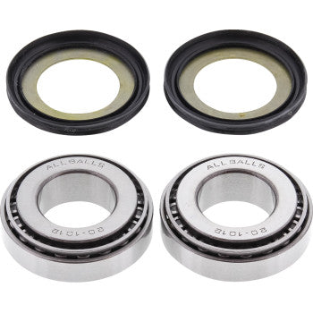 Two silver tapered roller bearings with engraved text and two black rubber seals with beige inner rings arranged side by.