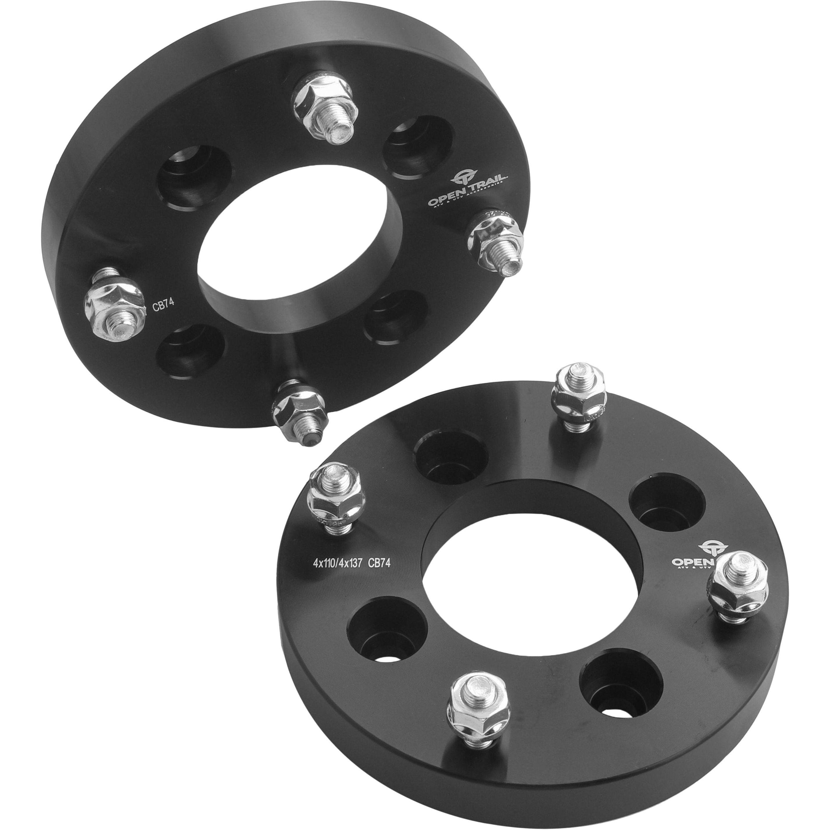 Two black Wheel Spacer Adapter 1 4/110 To 4/137 10Mm X 1.25Mm by Open Trail units with metal studs and bolts are displayed on a white background, one upright and one flat, showing bolt holes and engraved text for enhanced traction stability.