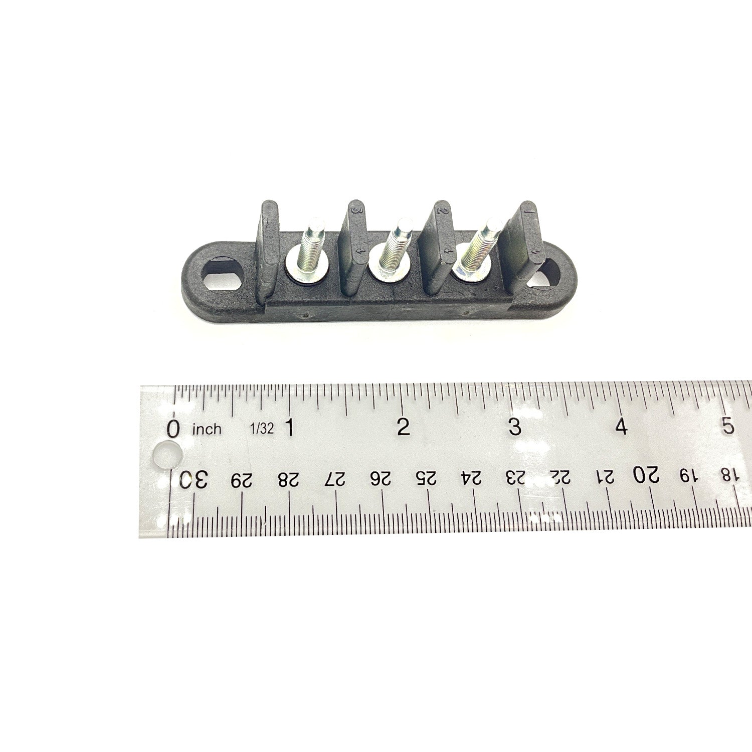 Black plastic 3-post terminal block with metal screw connectors next to a ruler for size.