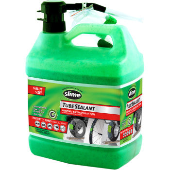 A large green 1-gallon container of Slime Tube Sealant with a black cap and clear hose, labeled for preventing and repairing bike tire flats, features product info and tire images on the front label.