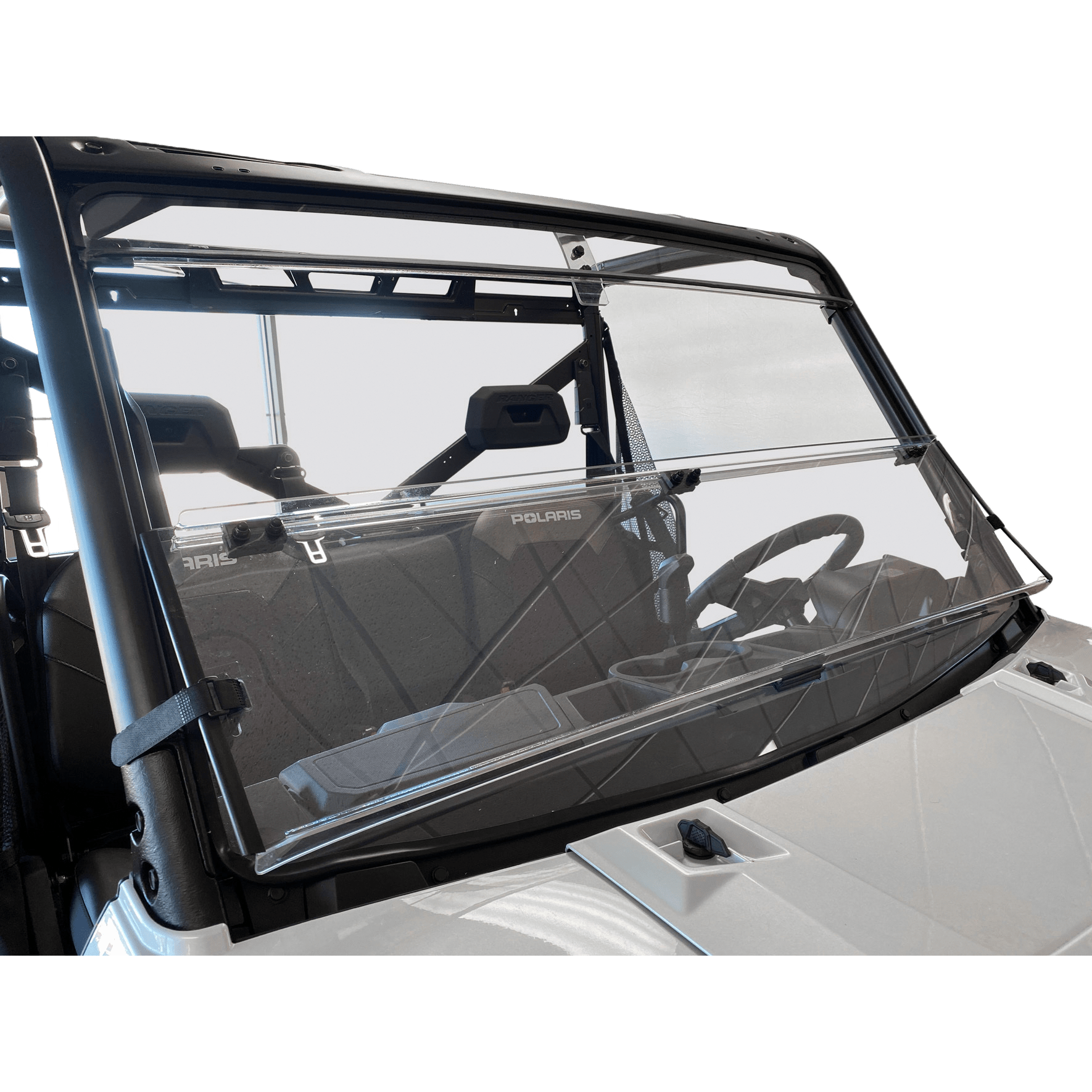 The Folding Windshield by Open Trail, a clear two-piece hinged design, is shown attached to the front of a white Polaris utility vehicle, revealing seats, steering wheel, and roll cage. Adjustable for airflow. Background is transparent.