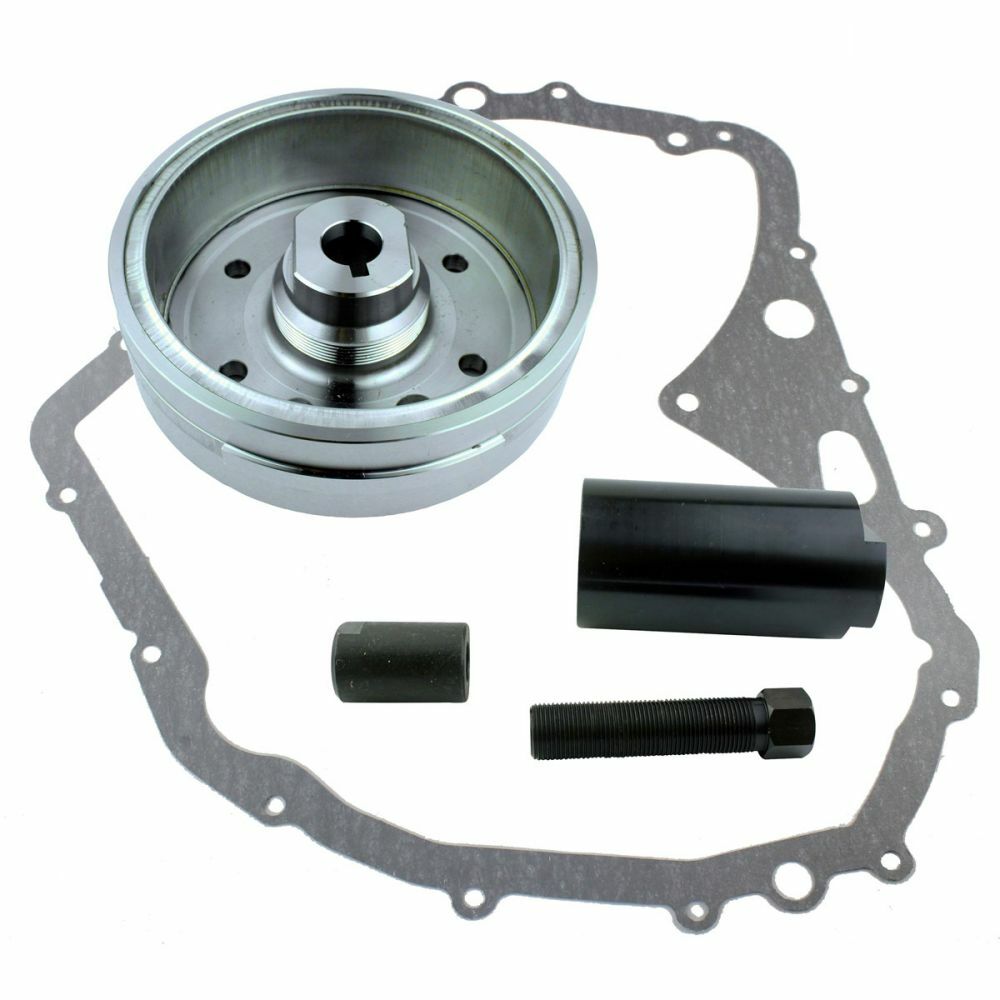Silver metal flywheel, black cylindrical spacers, bolt, and irregular gray gasket with multiple holes.