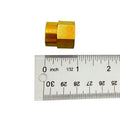 Small gold-colored metal spacer with hexagonal body, shown next to a ruler for scale.