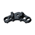 Matte black metal triple tree clamp with precise cutouts and mounting holes for motorcycle fork assembly.
