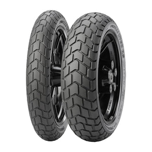 Two black front motorcycle tires with deep, block-pattern tread mounted on black metal rims.